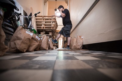 Bruno, au téléphone, dans le couloir avec les paniers de légumes, qui attend les gens venant chercher leur commande.